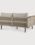 The Corbey Outdoor Sofa by Ethnicraft showcases woven rope sides and back, black metal legs, and a single wooden armrest—an inviting modern beige piece for any patio, pictured from the rear against a white background.