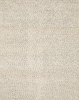 A close-up of the Quarry Rug - Ivory by Loloi, featuring a textured surface with small, irregular light-colored dots and subtle swirling patterns, crafted in 100% wool and resembling a hand-knotted design.