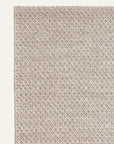 Close-up of the Sherpa Weave Rug - Chai by Armadillo&Co, showing its textured, diamond-patterned design angled in the corner against a light background.