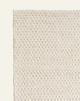 A close-up of the Armadillo&Co Sherpa Weave Rug - Sand shows its cream tone, raised diamond pattern, and tightly woven edges, set against a light beige background.