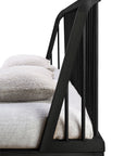 Close-up side view of the Ethnicraft Spindle Bed in black oak, featuring vertical slats and an angled headboard; shown with light sheets and two stacked pillows.
