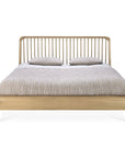 The Ethnicraft Spindle Bed - Oak features a modern design with a vertical slat headboard in European oak, shown from the front, topped with a beige textured comforter and two matching pillows.