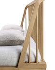 Side view of the Spindle Bed - Oak by Ethnicraft, crafted from European oak with vertical slats. Styled with a light gray mattress and two textured light-colored pillows for a minimalist, modern look.