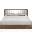 The Ethnicraft Spindle Bed - Teak features a spindle headboard and is shown from the front with light gray bedding and two matching pillows, set against a white background.