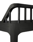 Close-up of the backrest and arm on the Ethnicraft Spindle Bench - Black Oak, showing vertical spindles in smooth, dark European oak set against a white background.