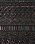 Close-up of the Tabwa Sideboard - 4 door by Ethnicraft, showcasing intricate tribal-inspired carvings with zigzags, diamonds, and vertical lines, reflecting Tabwa cultural influences on its dark wooden surface.