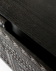 Close-up of the Ethnicraft Tabwa TV Cupboard - 94 shows a hand-carved linear geometric motif on the partially open drawer and a subtle wood grain texture on the top.
