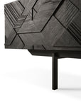 A close-up of the Ethnicraft Graphic TV Cupboard - 63 showcases its modern black finish, geometric textured patterns, and slim black metal legs, set against a white background.