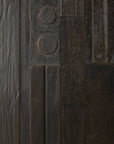 Close-up of the Ethnicraft Mosaic Sideboard - 3 doors, highlighting its dark wood surface with exceptional craftsmanship, featuring varied textures, vertical panels, raised circles, and a mix of grooved and smooth rectangular sections.