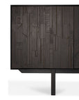 Close-up of the Ethnicraft Mosaic Sideboard - 4 door, a modern cabinet with geometric textured dark wood panels, designed by Alain van Havre. The piece features slender black legs and is set against a white background.