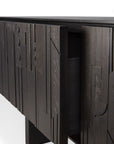 A close-up of Ethnicrafts Mosaic TV Cupboard - 64 highlights its dark geometric wooden doors, designed by Alain van Havre, with one door ajar to show a dark interior against a plain white background.