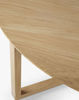 Close-up of the Ethnicraft Tripod Coffee Table - Oak, highlighting a portion of its smooth, round European oak tabletop and one angular leg, all set against a white background for timeless European style.