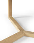 Close-up of the Ethnicraft Tripod Coffee Table - Oak shows its light oak leg structure, with three beams joining at a central point, set against a white background.
