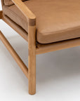 Close-up of the Troubadour Lounge Chair | Leather • Light Oak by Wooden Stories, featuring a solid oak frame, light brown cushioned leather seat and backrest, smooth rounded edges, and a simple modern design inspired by classic Danish style.