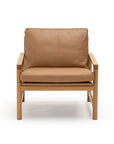The Troubadour Lounge Chair by Wooden Stories features tan leather cushions and a light oak frame, inspired by Danish design. Shown from the front against a white background.