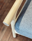 Close-up of the SOBU Viking Lounge Chair - White Ash, featuring a solid ash wood frame and light gray high-density foam cushion, shown on a wooden floor.