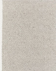 A close-up of the corner of the Winnow Rug - Alabaster by Armadillo&Co shows its light gray, textured basket-weave pattern on a neutral background.