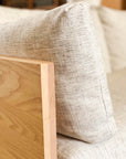 Close-up of SOBUs Woody Sofa SAMPLE_(DZ): a light beige cushion with high-density foam rests against the natural-finish solid ash wood armrest, highlighting distinct grain patterns.