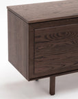 Close-up of the Yorke Sideboard by Wooden Stories in dark wood with visible grain, featuring rectangular legs against a white background—a refined example of Scandinavian design.