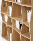 The Z Rack Small - Oak by Ethnicraft features irregular, wavy shelves in European oak. Its natural finish, scattered books, and empty spaces highlight organic design elements alongside classic European refinement.