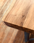 Close-up of the Leviathan Live Edge Counter Table by Moes, showcasing its rich acacia grain, knots, and texture. Set on a hardwood floor, the table highlights natural beauty with its distinctive live edge design.
