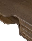 A close-up of the Flow Desk by Ethnicraft captures its smooth, curved corner and a portion of the drawer with a carved handle. Crafted from solid mahogany, this desk showcases a polished, rich brown finish—an elegant example of modern workspace furniture.