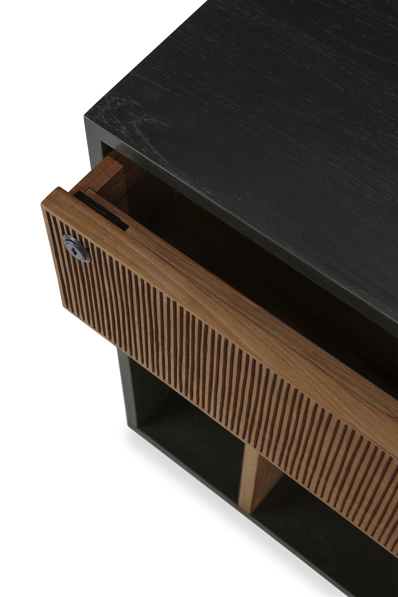 A close-up of the Ethnicraft Oscar Drawer Unit showcases its modern black cabinet design with an open solid teak drawer featuring vertical grooves and a keyhole on the left side—embodying timeless style that’s perfect for office storage.