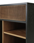 Close-up of the Ethnicraft Oscar Drawer Unit—a modern wooden cabinet featuring a grooved drawer front, black outer frame, and open shelves with natural wood finishes. Expertly crafted from solid teak, its design showcases clean lines and contrasting wood tones, making it ideal for stylish office storage.