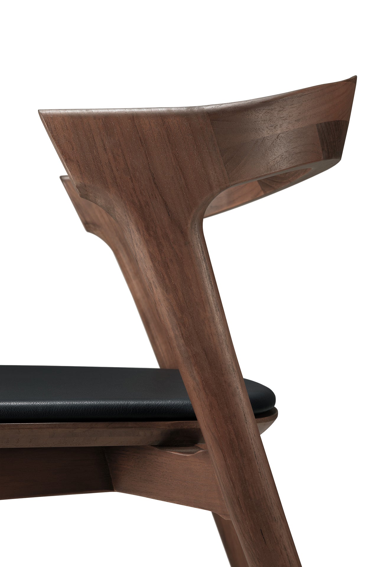 Close-up side view of the Ethnicraft Bok Dining Chair - Teak Brown, showcasing its solid teak frame, curved backrest, black leather seat cushion, smooth contours, and natural wood grain.