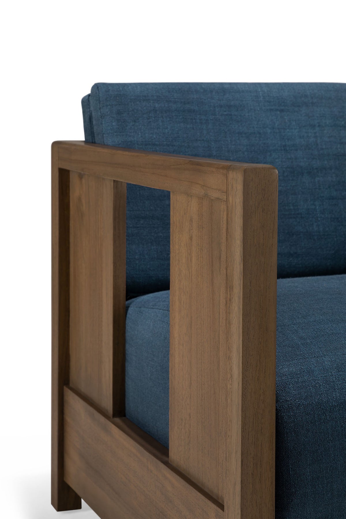 A close-up of the Ethnicraft Roan Lounge Chair | Ink, a modern wooden armchair with ink blue upholstered cushions and backrest, featuring rectangular wooden armrests and clean, minimalist lines inspired by vintage design.
