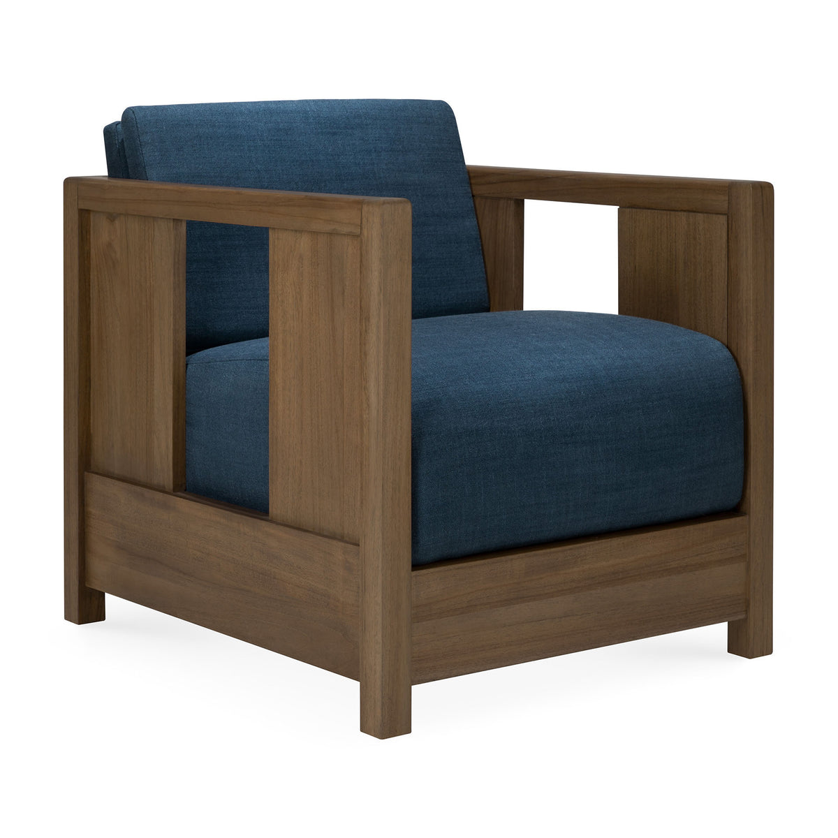 The Roan Lounge Chair | Ink by Ethnicraft features a modern, vintage-inspired design with a sturdy wooden frame, clean lines, wide blue upholstered seat and backrest, and open rectangular armrests for a stylish yet timeless appeal.
