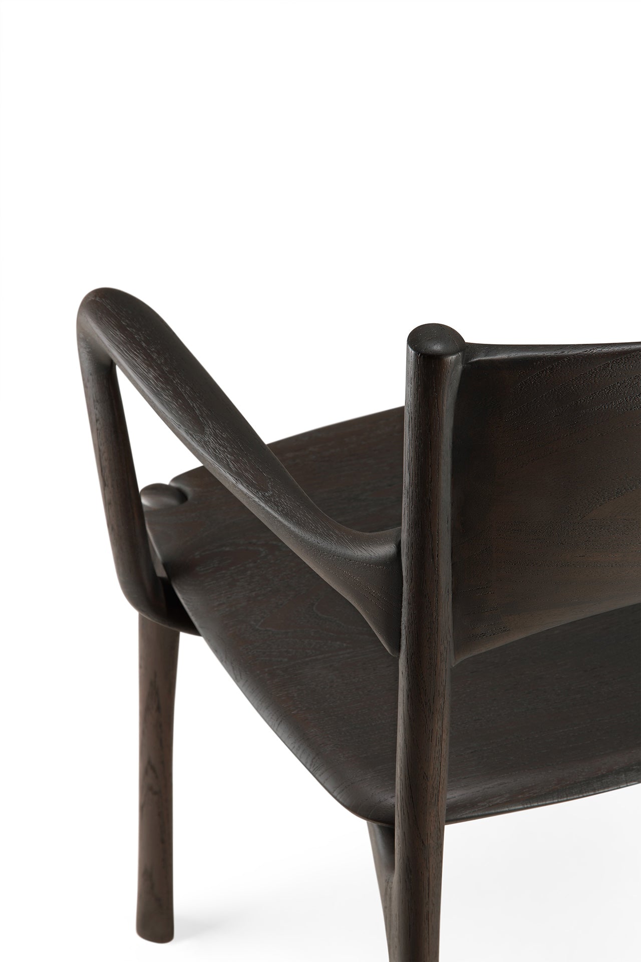 A close-up of the Ethnicraft PI Dining Chair - Teak Dark Brown with arms, highlighting its curved backrest and smooth, sculpted lines against a white background—showcasing the elegance of handcrafted design.