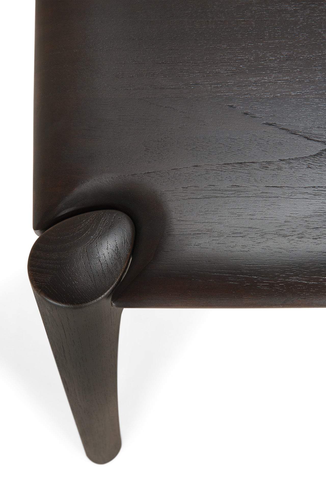 Close-up of the Ethnicraft PI Dining Table - Teak Dark Brown, featuring a smoothly sculpted solid teak leg with visible wood grain and fine craftsmanship, set against a white background.