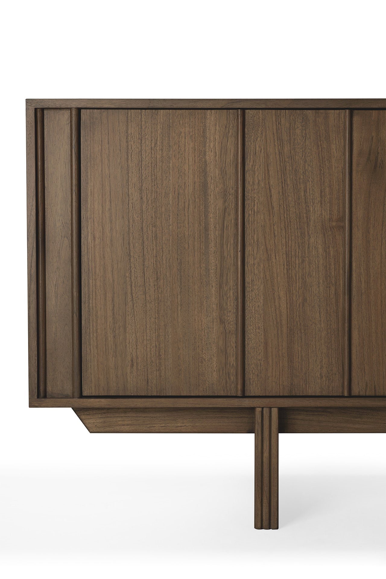 A close-up of the Ethnicraft Pillar Sideboard - Teak Wild Brown shows its vertical panels, minimalist design, and clean lines; only part of the solid wood front and one leg appear against a white background.