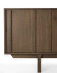 A close-up of the Ethnicraft Pillar Sideboard - Teak Wild Brown shows its vertical panels, minimalist design, and clean lines; only part of the solid wood front and one leg appear against a white background.