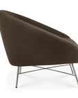Side profile of a dark brown Barrow Lounge Chair - Paon by Ethnicraft, featuring a curved backrest and a slender metal crossed-leg base.