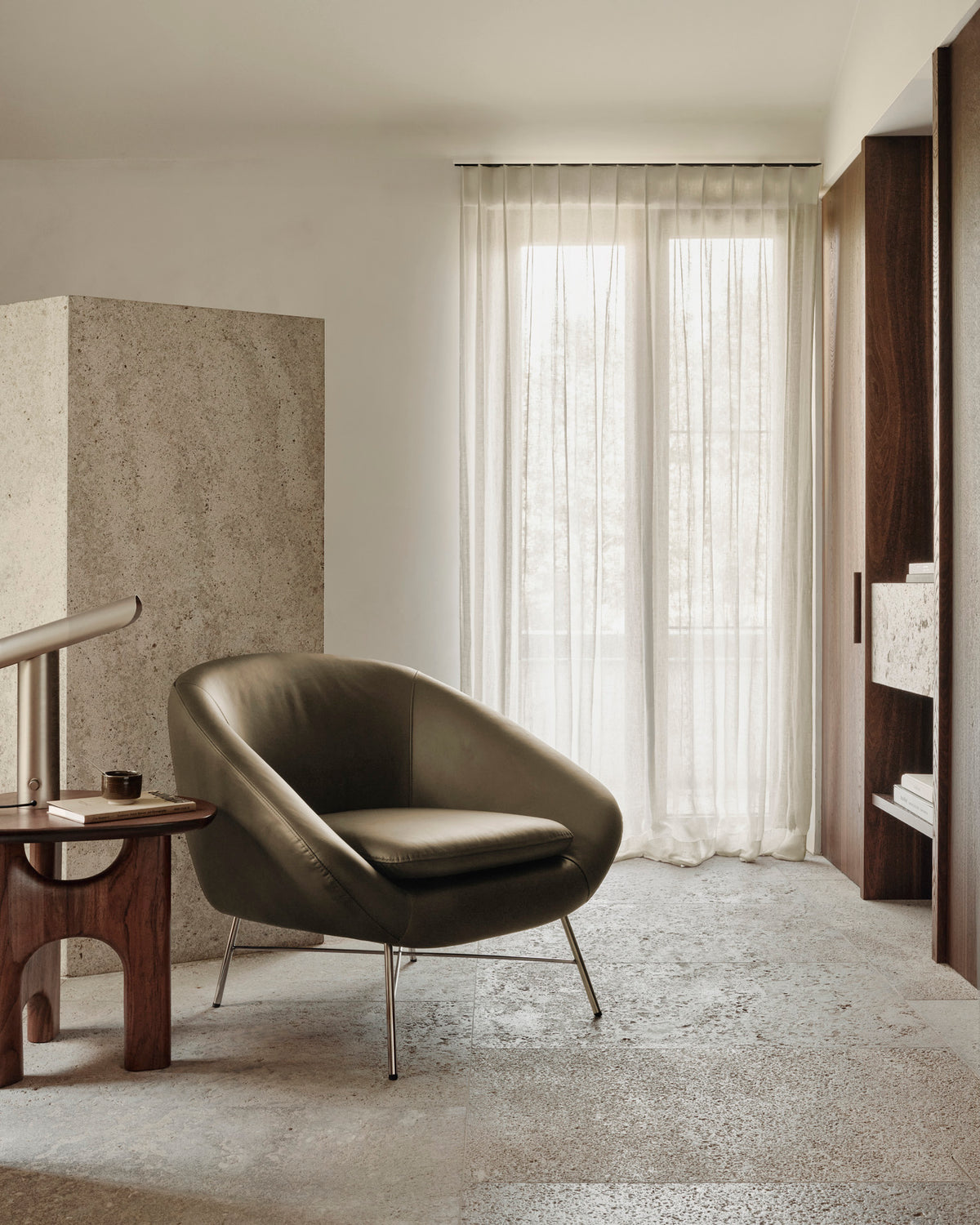 Olive green leather Ethnicraft Barrow Lounge Chair - Green Leather with a curved back and thin metal legs, positioned next to a wooden side table.