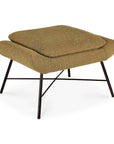 The Ethnicraft Barrow Footstool - Ginger features a cushioned, textured brown seat and black metal legs—ideal for vintage furniture enthusiasts. Set against a white backdrop, it blends modern design with retro charm.