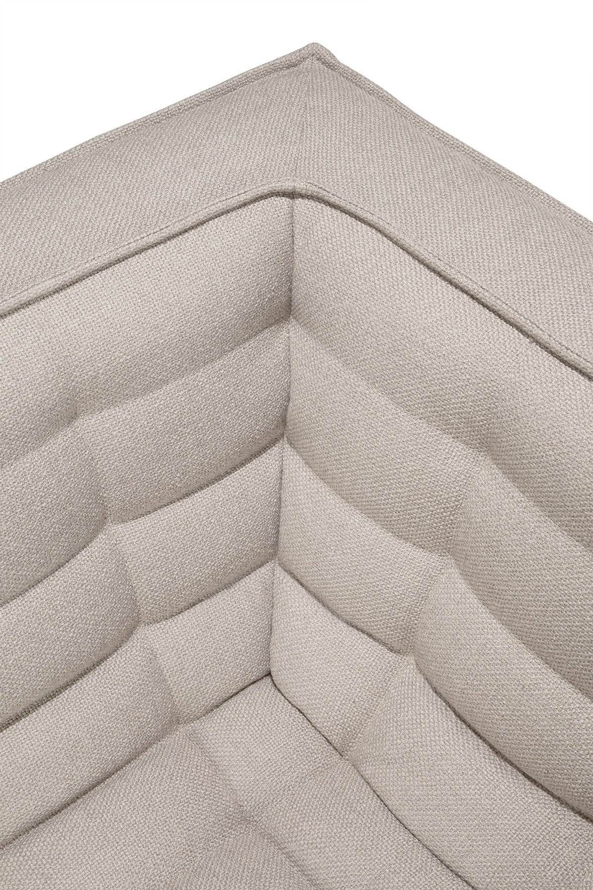 A close-up view of the corner of the N701 2-Seater Sofa in beige by Ethnicraft highlights its textured, tufted fabric and quilted cushion design, showcasing exceptional European craftsmanship.