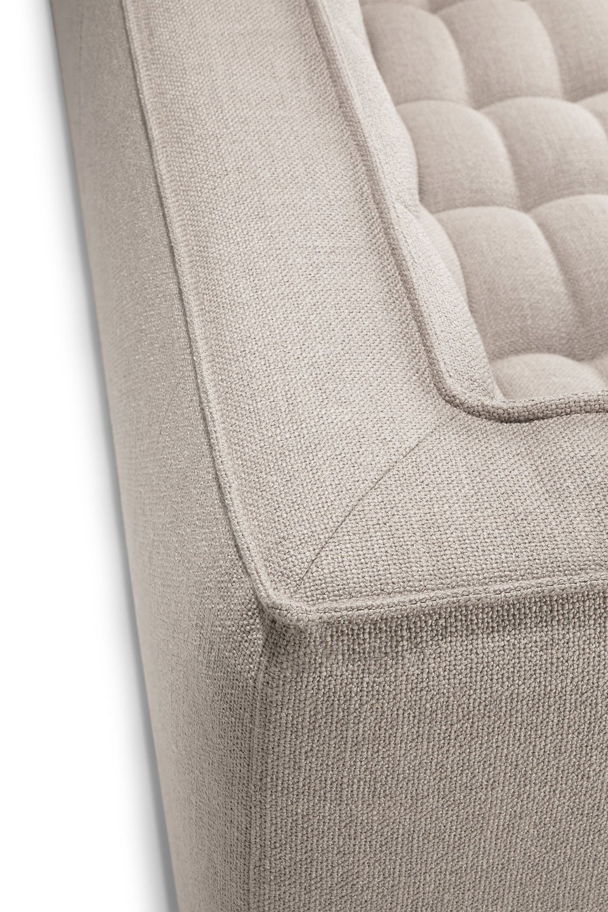 Close-up of the corner of the Ethnicraft N701 2-Seater Sofa in beige, showcasing its tufted cushioning and textured upholstery fabric, and highlighting the sofa’s refined modular design.