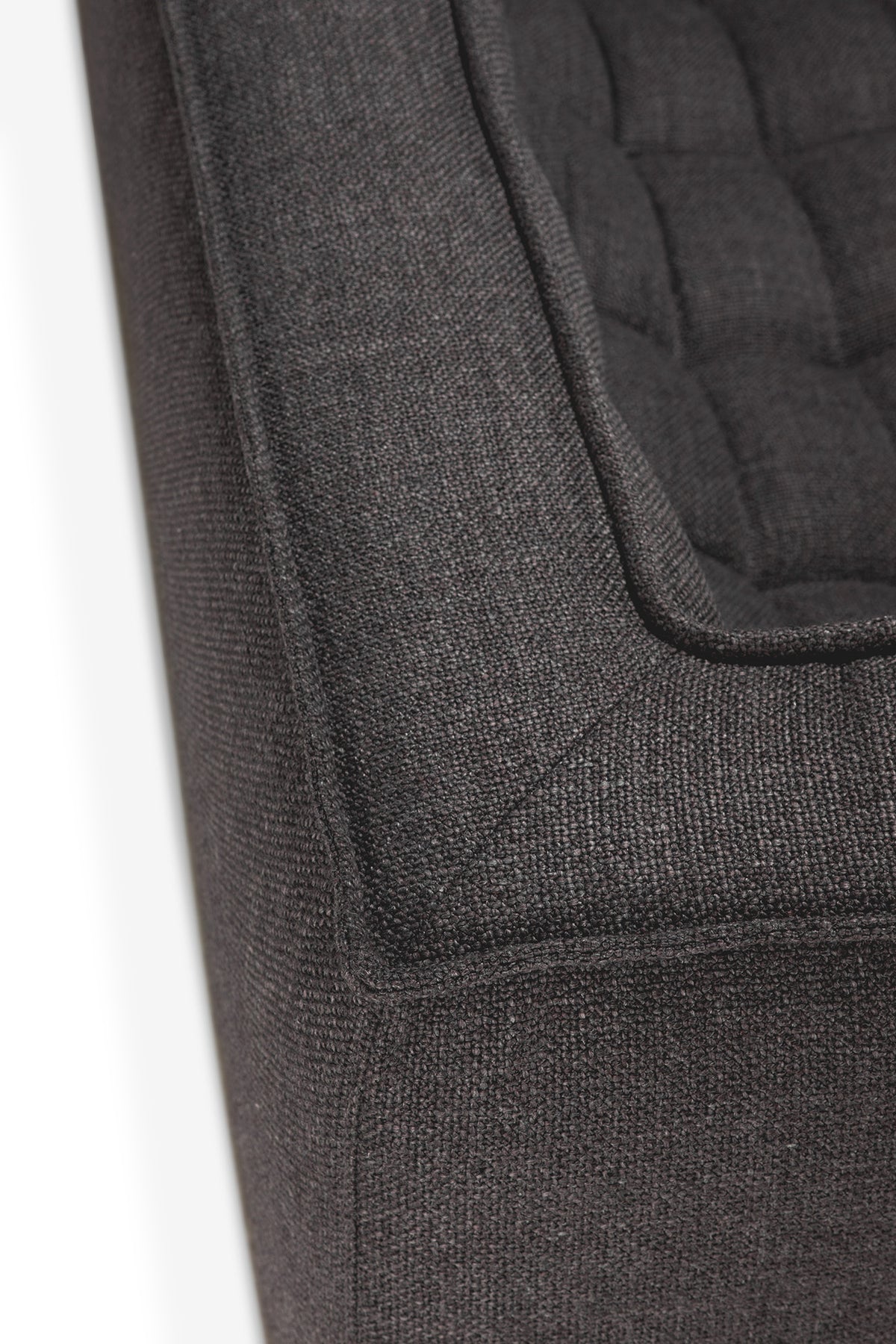 Close-up of the corner of the Ethnicraft N701 2-Seater Sofa in Dark Grey, featuring textured fabric with tufted cushions that highlight its detailed stitching and European-inspired upholstery design.