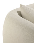 Close-up of the Figur Sofa | 2 seater by Ethnicraft—a modern, cream-colored textured fabric sofa featuring rounded armrests and a matching cushion. This piece effortlessly blends comfort with timeless design, making it an ideal addition to any contemporary living space.