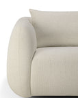 Close-up of the Ethnicraft Figur Sofa | 2 seater, showcasing its modern curved design in textured beige fabric with a coordinating rectangular cushion, set against a white background—ideal for contemporary interiors.