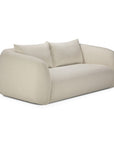 The Figur Sofa | 2 seater by Ethnicraft features a soft, minimalist design in light beige, with rounded, oversized arms and backrest, complemented by two matching back cushions. This modern loveseat sits directly on the floor without visible legs, making it an ideal addition to contemporary living spaces.