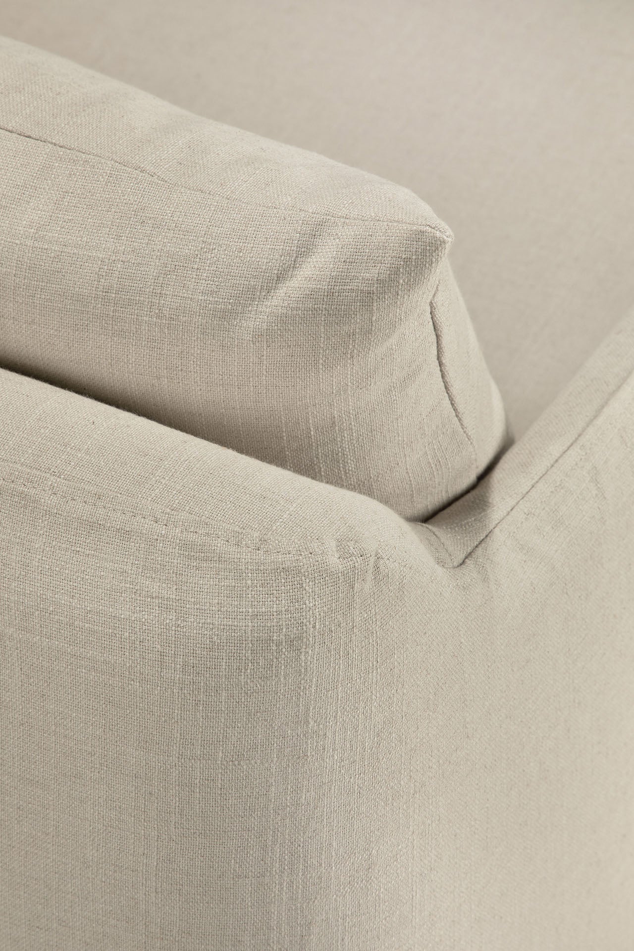 Close-up of the Ethnicraft Weave Lounge Chair - Bone, focusing on the corner where the armrest meets the backrest to highlight the upholstery's textured bone-colored linen-blend fabric and detailed seams.