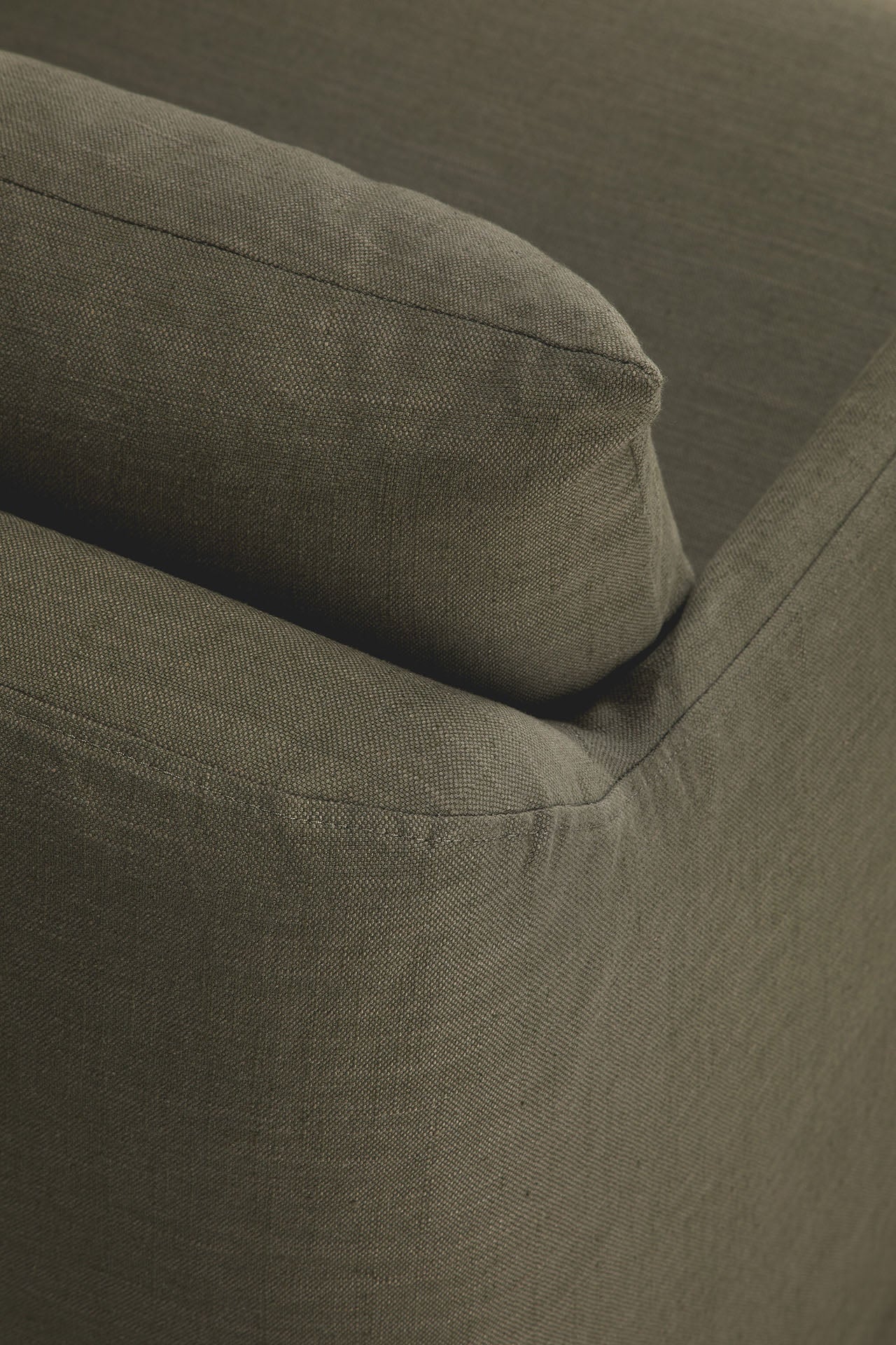 Close-up of the corner of Ethnicraft's Weave Lounge Chair in green, showing the textured fabric and cushion edge, highlighting the brand's signature style.