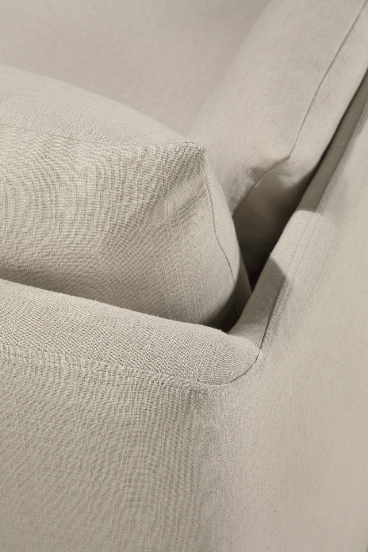 Close-up of a beige fabric sofa corner, highlighting the detailed texture of the linen-blend upholstery and the precise seam lines on the cushion and armrest. The Ethnicraft Weave Sofa | 2 Seater Bone features a removable slipcover that blends style with practicality, making it ideal for contemporary living spaces.