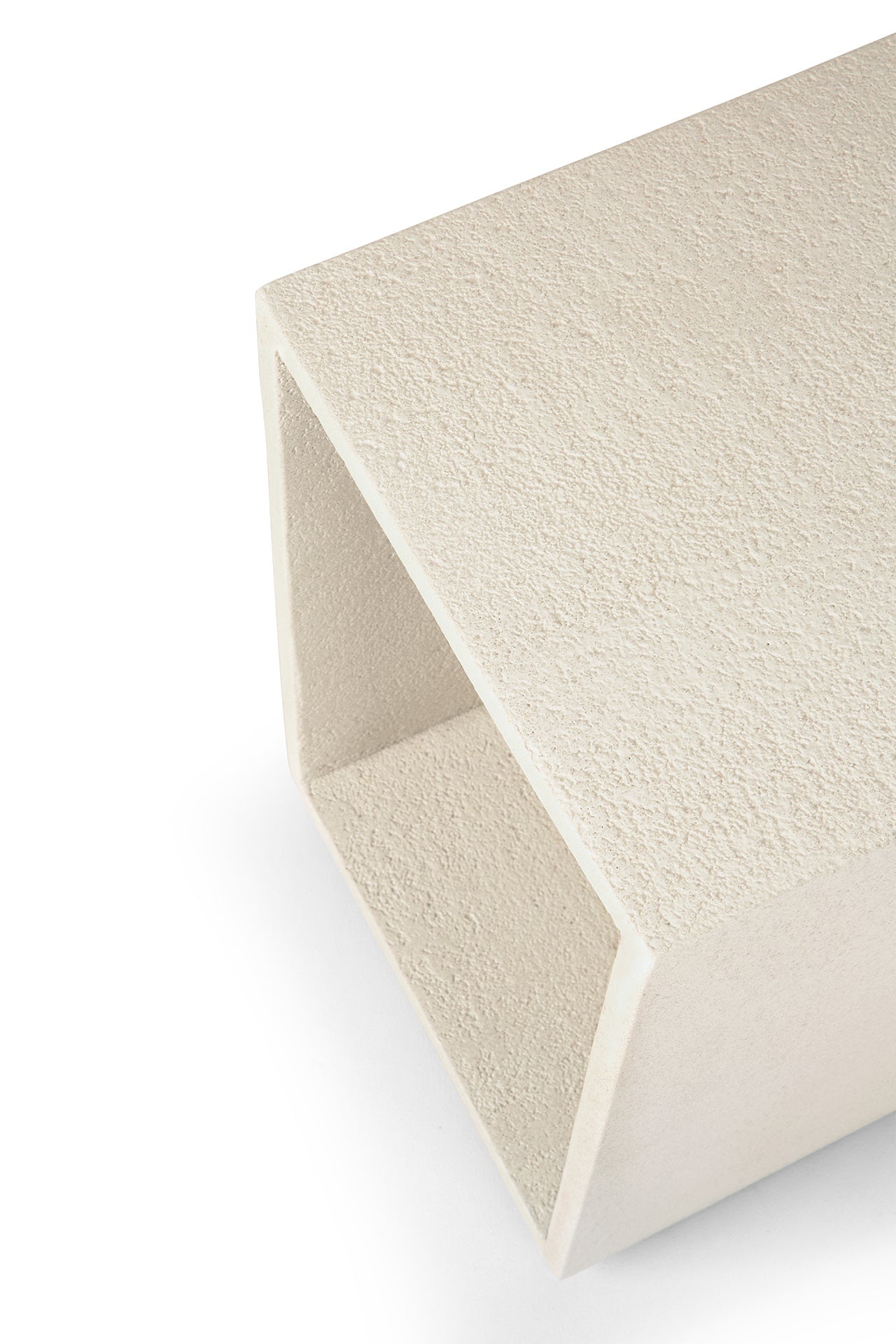 A close-up of the Elements Bedside Table by Ethnicraft, showcasing its rectangular, hollow form and textured Microcement-inspired surface from the Elements collection, photographed against a white background.