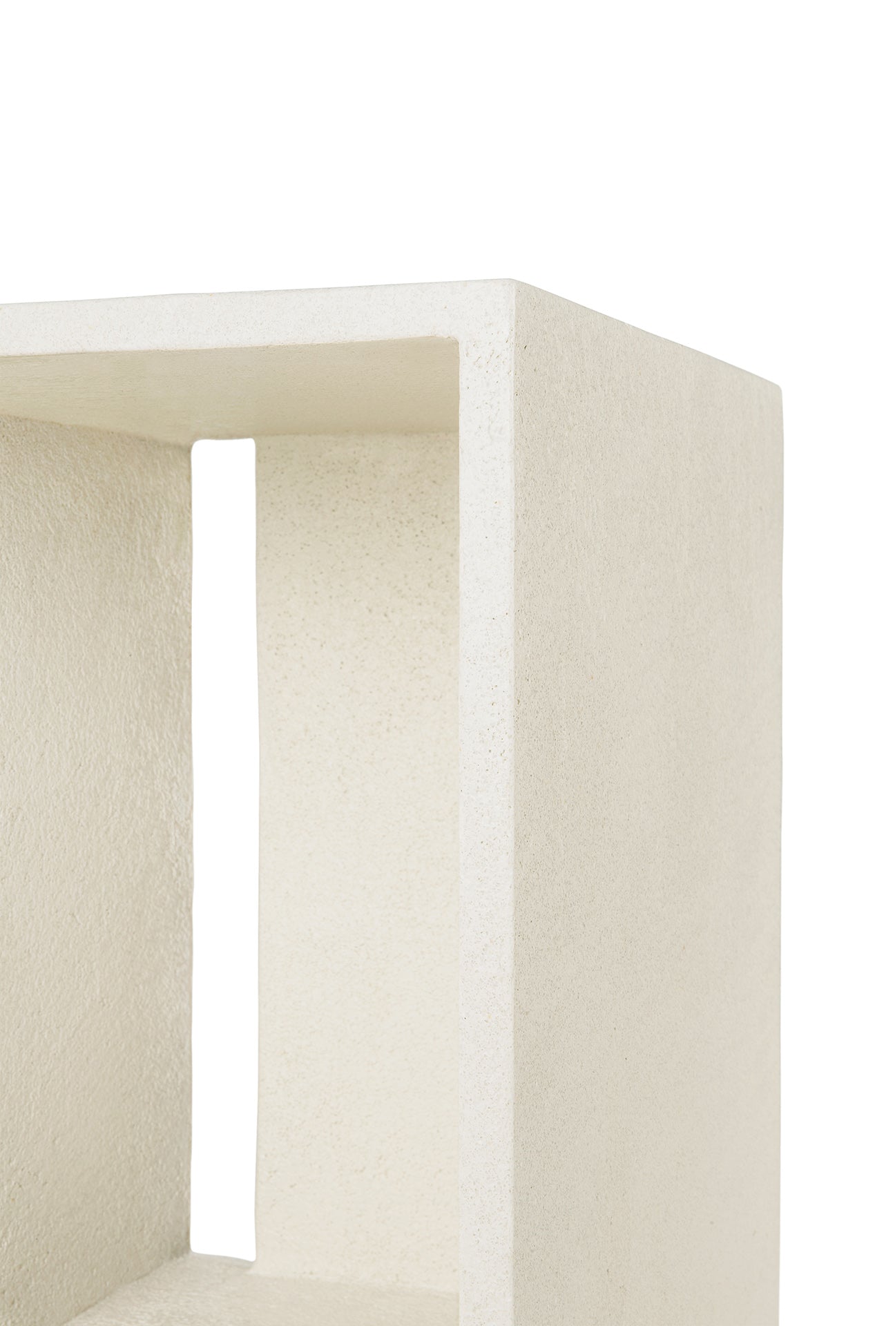 Close-up of the corner of Ethnicraft’s Elements Bedside Table, showcasing its minimalist off-white rectangular form, geometric open design, and microcement-textured surface.