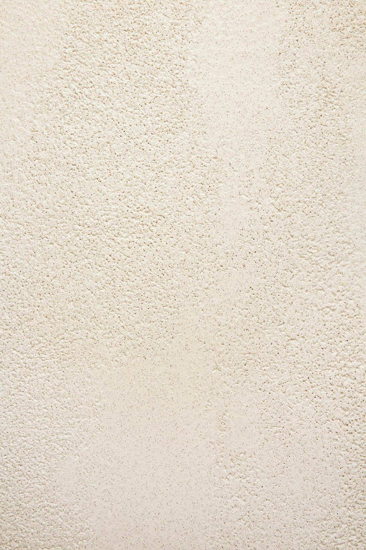 Close-up of a textured, off-white plaster wall with a subtly rough, grainy finish reminiscent of microcement, inspired by the Elements Bedside Table from Ethnicraft.